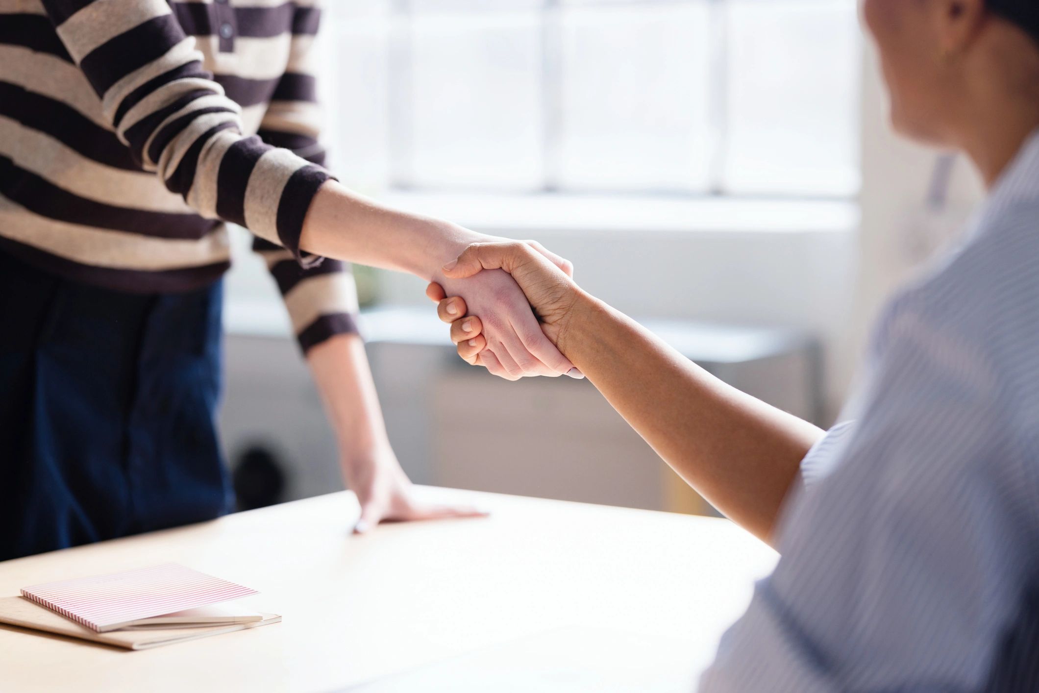 Business partners shaking hands across a desk